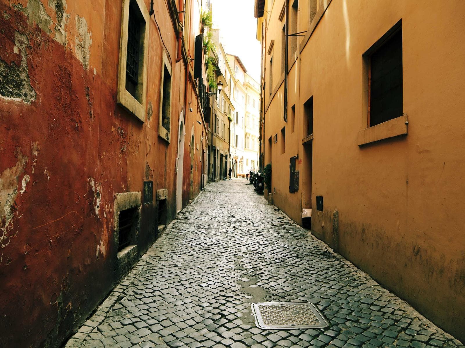 Vicolo acciottolato tra muri ocra e terracotta