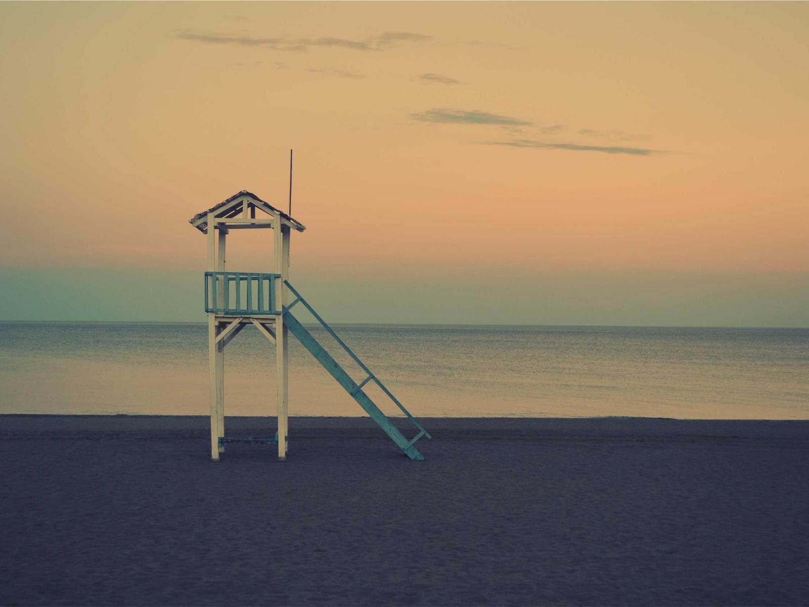 Sedia del bagnino su una spiaggia al tramonto